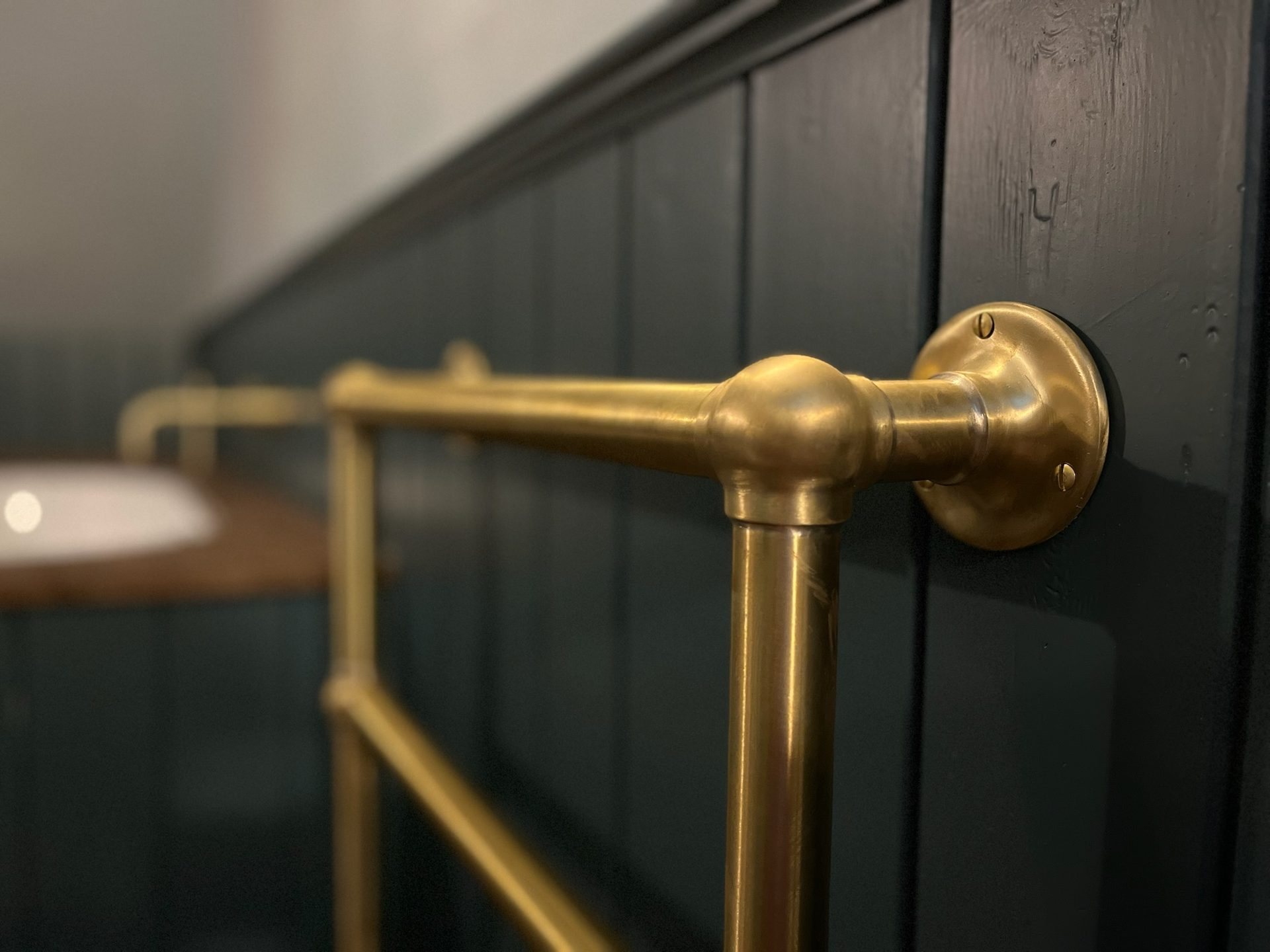 Brass towel rail on green boarding